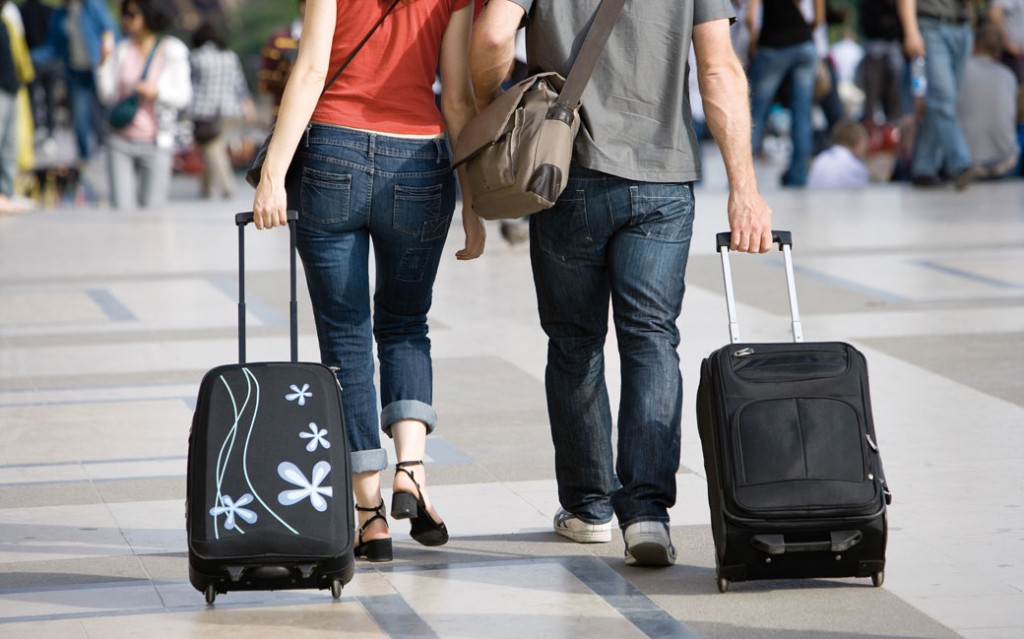 Couple walking outdoors with rolling luggage